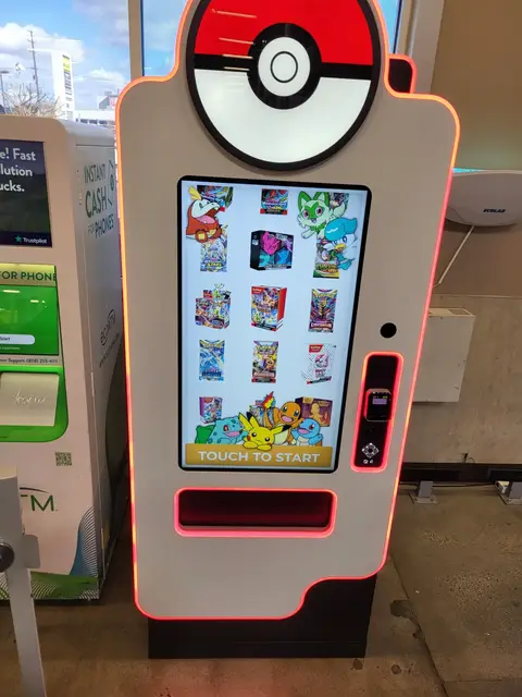 A white vending kiosk and a green ecoATM phone kiosk side by side in a store entry