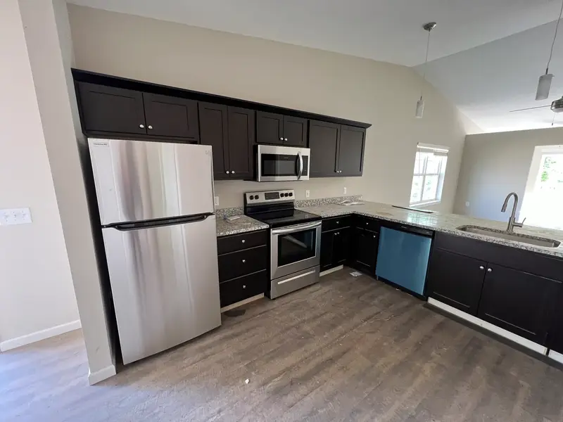 A new kitchen with a stainless steel refrigerator, range, over-range microwave and dishwasher