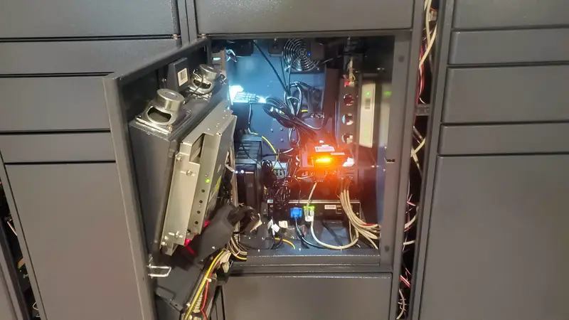 Open locker service door showing wiring, modules with an orange status light, a router and a fan