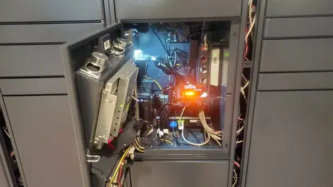 Open locker service door showing wiring, modules with an orange status light, a router and a fan