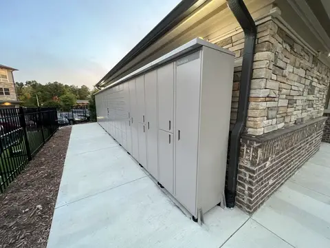 A long row of outdoor lockers installed on a concrete pad beside a building