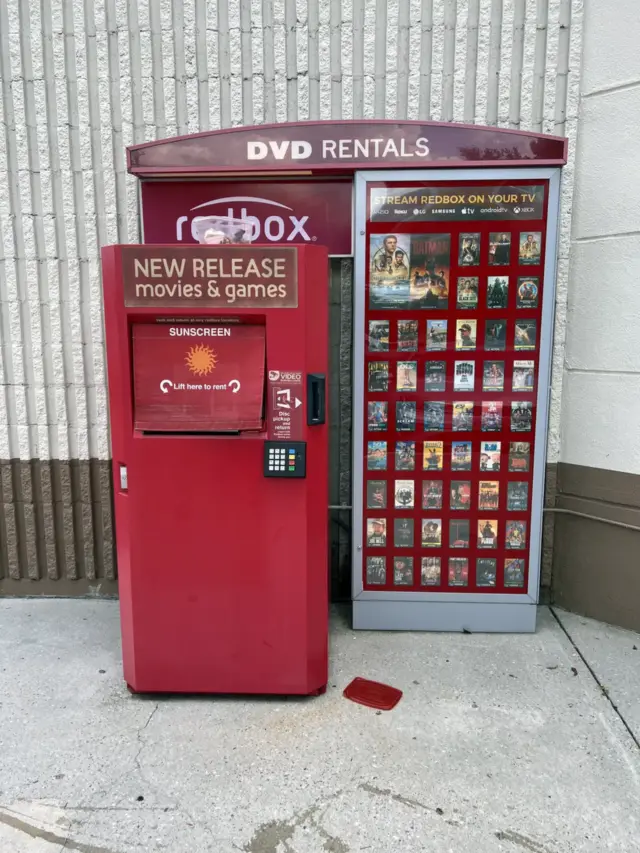 A rental kiosk standing against a ribbed wall outdoors